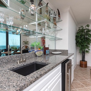 Savor drinks at the wet bar area, with a stylish display of glassware, wine cooler, and a view that invites relaxation