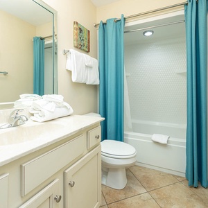 Inviting guest bathroom featuring a spacious vanity, fresh towels, and a relaxing tub/shower combo with teal accents