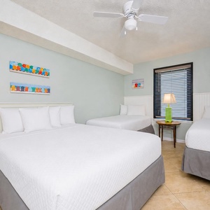 Feel relaxed in this guest bedroom, featuring a queen bed, two twin beds, and playful decor