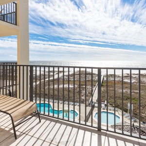 Relax on the balcony lounger while enjoying views of the beach and the inviting pool area below
