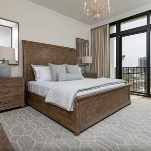 The master bedroom features a stunning view, king bed, a stylish chandelier, and elegant wooden furnishings