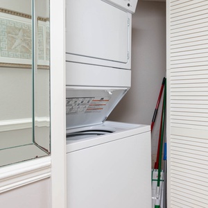 Washer and dryer combo tucked in a closet, complemented by a decorative starfish print and cleaning supplies nearby