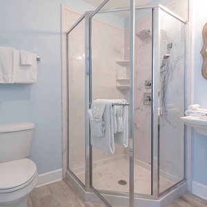 Enjoy a relaxing shower after a day at the beach in this guest bath with stylish accents and fluffy towels