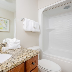 Refreshing guest bath featuring a granite countertop, fresh towels, and a clean tub/shower combo for a relaxing stay