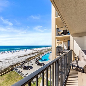 Enjoy a serene view from the balcony overlooking the beach and pool area, with comfortable seating for relaxation