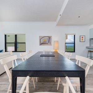 Bright and airy dining area featuring a sleek black table, modern decor, and inviting views through large windows