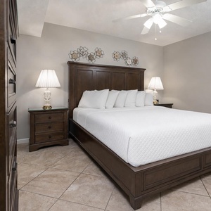 This serene bedroom features a king bed with crisp white linens, elegant lamps, and tasteful wall decor for a restful retreat