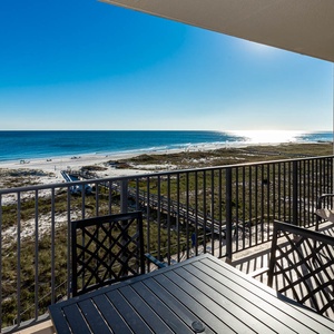 Inviting balcony with a table and chairs offers a panoramic view of the beach and tranquil gulf waters