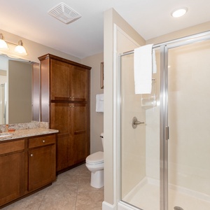 Enjoy a relaxing shower after a day at the beach in this guest bath with stylish cabinetry and spacious vanity
