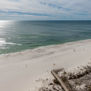 Expansive view of a tranquil beach with soft white sand and gentle waves, inviting relaxation and outdoor exploration