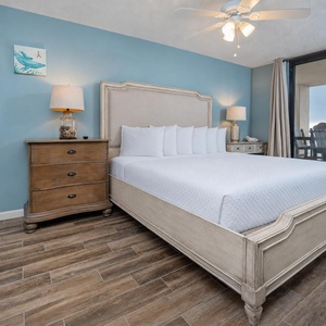 Relax in this serene master suite featuring a king bed, soft blue walls, and easy access to the beach balcony