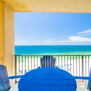 Relax on the balcony with table and chairs, enjoying the serene beach view and sparkling waters below