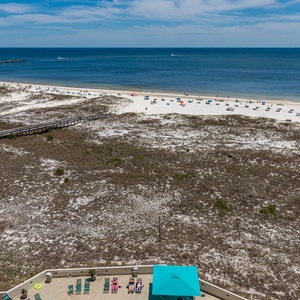 Expansive view of the beach with white sand and colorful umbrellas, showcasing a serene coastal atmosphere from the balcony