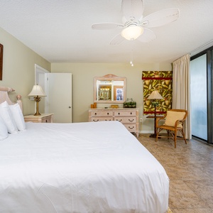 Master suite featuring a king bed, a stylish dresser, and access to a balcony with views of the surrounding area