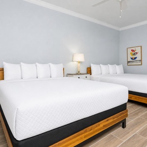 Soothing guest room featuring two queen beds, a stylish lamp, and cheerful coastal artwork