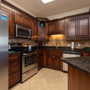 Rich wooden cabinetry and granite countertops highlight this kitchen, featuring a breakfast bar and ample storage space