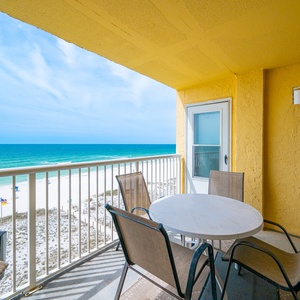 Enjoy stunning beachfront views from this cozy balcony, featuring a round table and comfortable seating for relaxation
