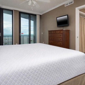 Relaxing guest bedroom featuring a king bed, a TV, and expansive windows showcasing a lovely coastal view