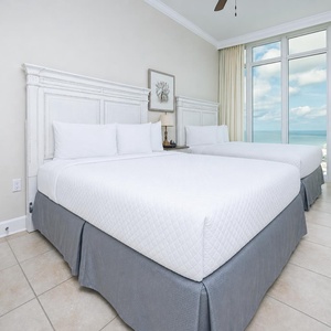 Unwind in this inviting guest bedroom featuring two queen beds, soft linens, and stunning beach views
