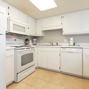 White cabinetry complements the fully-equipped kitchen, featuring a convenient coffee maker and ample counter space