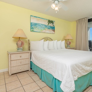 The master suite features an inviting king bed, with sliding glass doors leading to a balcony overlooking the beach