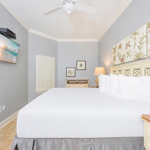 Cozy guest bedroom featuring a plush king bed, wall-mounted TV, and soothing coastal decor for a relaxing getaway