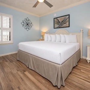 Unwind in the serene bedroom featuring a king bed, soft blue walls, and natural light from the window