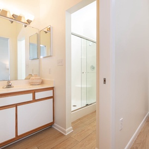 Master bathroom featuring a sleek vanity, large mirror, and a glass-enclosed walk-in shower for a refreshing experience