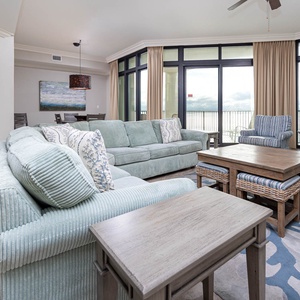 This living area features soft blue seating, coastal decor, and large windows offering a stunning beach view