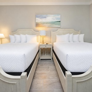 Rest comfortably in this guest bedroom featuring two queens and soft lighting from lamps on the nightstands