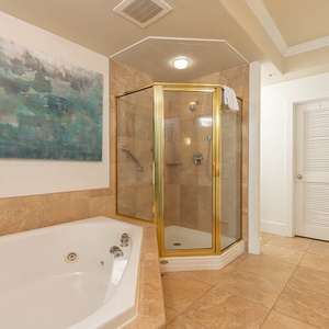 The master bathroom features a luxurious jetted tub, a glass shower, and calming blue artwork, perfect for relaxation