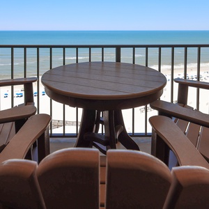 Relax on the balcony with comfortable seating and breathtaking views of the serene beach and vibrant umbrellas below