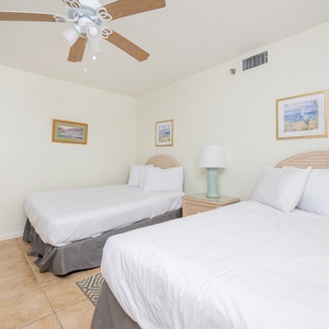 Inviting guest bedroom featuring two double beds, coastal decor, and a ceiling fan for added comfort