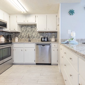 The kitchen features stainless appliances, granite countertops, and cheerful coastal decor for a delightful experience