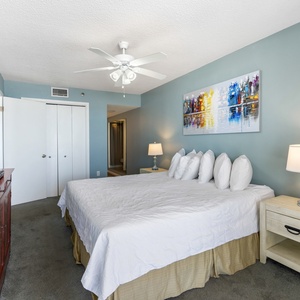 Brightly colored artwork complements the inviting master bedroom with a king bed, bedside lamp, and a mounted TV