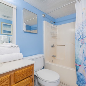 Towels stacked on the counter invite you to refresh after a day of coastal family fun in this guest bath
