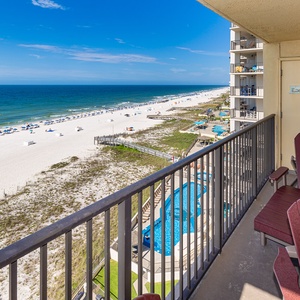 Spacious balcony features a round table with four chairs, offering a serene view of the tranquil beachfront and azure waters