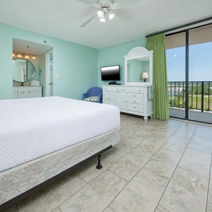 The master suite features a comfortable king bed, a TV, and sliding doors that open to a lovely view of the surroundings
