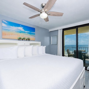 Brightly decorated master suite featuring a king bed, a TV, and balcony access with a beach front view