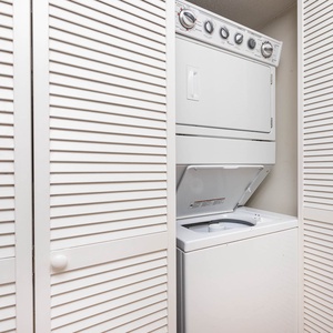 This laundry area features a stacked washer and dryer behind stylish louvered doors for convenient in-unit laundry