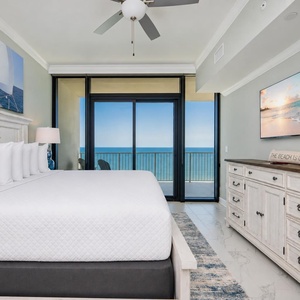 Relax in the master bedroom with a king bed, coastal decor, and expansive views through sliding glass doors