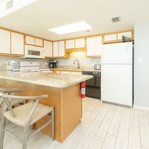 Kitchen features a granite countertop, white cabinetry, and a breakfast bar with seating for four