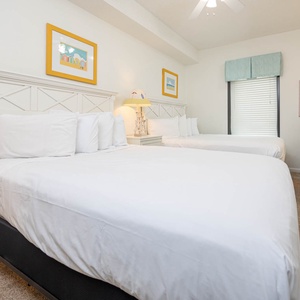 Rest in this guest bedroom featuring two comfortable queen beds, cheerful decor, and a TV