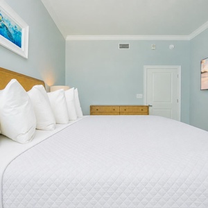 Unwind in this tranquil guest bedroom featuring a king bed, soft pillows, and a large TV