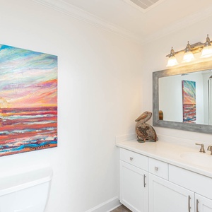 Brighten your morning routine in this stylish guest bath featuring a large mirror, artistic decor, and ample counter space