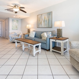 This bright living area features a cozy blue sofa, stylish armchair, and a flat-screen TV, perfect for relaxation