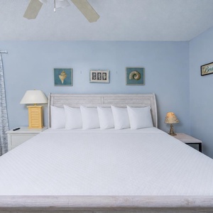 This bedroom features a light blue color scheme, a comfortable bed with white linens, and charming coastal decor