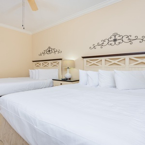 Calming guest bedroom featuring two comfortable beds, queen and double, and elegant decor for a relaxing stay