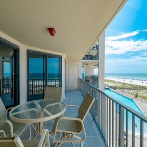 Relax at the outdoor table, enjoying refreshing breezes and views of the beach and gradual entry pool from your balcony