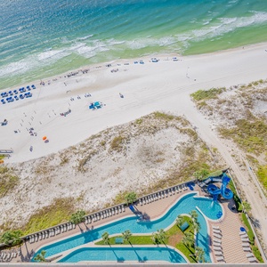 Experience beach fun with a stunning view of the lazy river, waterslide, and shoreline, perfect for a relaxing retreat